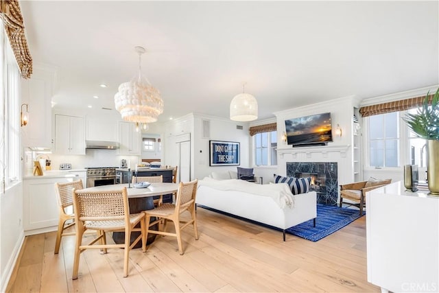 7161/2 Iris Ave, Corona Del Mar, CA 92625 - dining space with plenty of natural light, a high end fireplace, light wood-style flooring, a chandelier, and crown molding