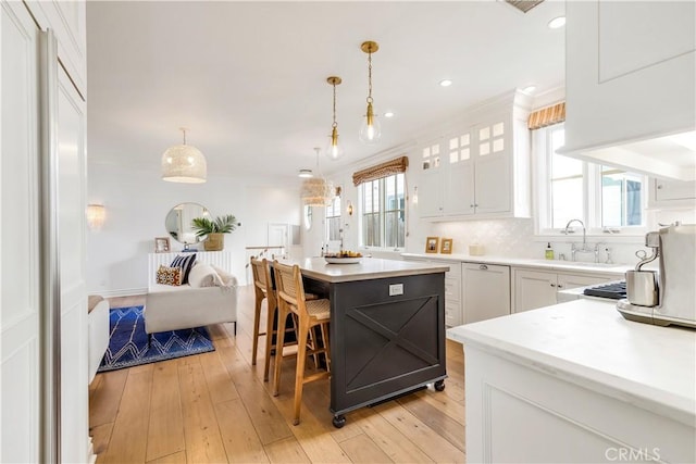 7161/2 Iris Ave, Corona Del Mar, CA 92625 - kitchen with light countertops, white cabinetry, a sink, light wood-type flooring, and ornamental molding