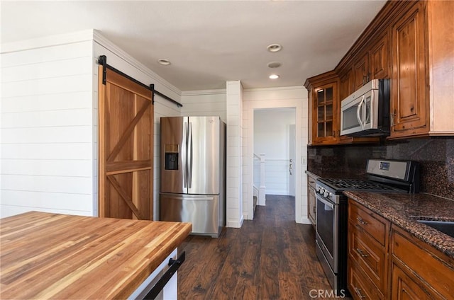 36055 Maddalena Rd, Winchester, CA 92596 - kitchen with appliances with stainless steel finishes, a barn door, dark stone counters, glass insert cabinets, and dark wood-style floors
