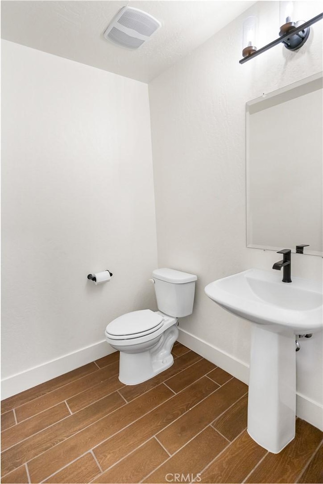 522 Sansoni St, Los Banos, CA 93635 - half bathroom with wood finished floors, toilet, baseboards, and a sink
