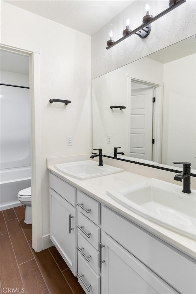 522 Sansoni St, Los Banos, CA 93635 - bathroom featuring double vanity, toilet, wood tiled floors, and bathing tub / shower combination