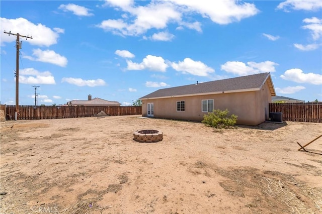 7841 Fernwood Ave, California City, CA 93505 - back of house featuring an outdoor fire pit, cooling unit, a fenced backyard, and stucco siding