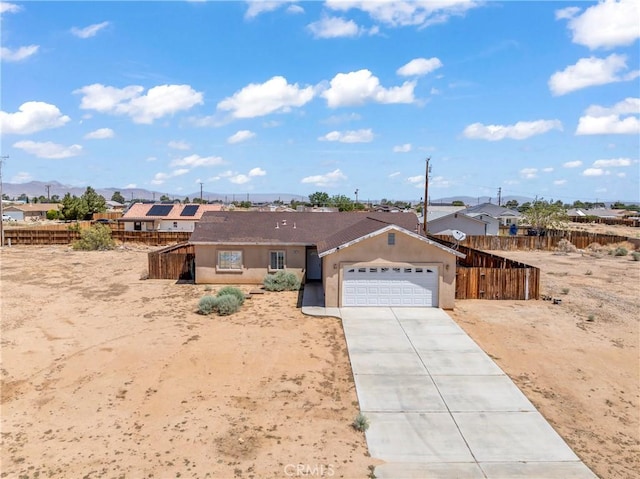 7841 Fernwood Ave, California City, CA 93505 - ranch-style home with a garage, concrete driveway, a mountain view, and stucco siding