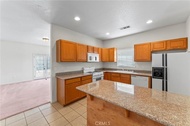7841 Fernwood Ave, California City, CA 93505 - kitchen with white appliances, a sink, light carpet, light stone countertops, and brown cabinets