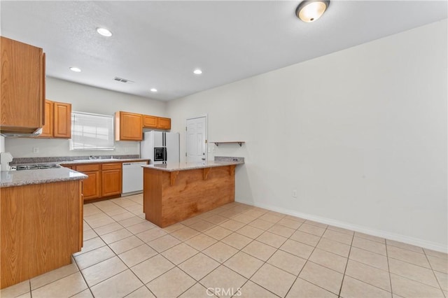 7841 Fernwood Ave, California City, CA 93505 - kitchen featuring white appliances, a peninsula, light tile patterned flooring, recessed lighting, and a kitchen breakfast bar
