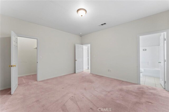 7841 Fernwood Ave, California City, CA 93505 - unfurnished bedroom featuring light colored carpet, a spacious closet, connected bathroom, and baseboards