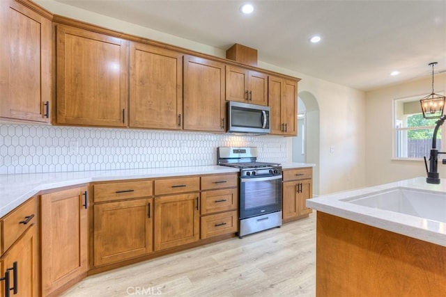 6210 Himmel St, Paradise, CA 95969 - kitchen with appliances with stainless steel finishes, brown cabinets, light wood finished floors, a sink, and arched walkways