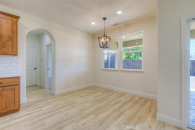 6210 Himmel St, Paradise, CA 95969 - unfurnished dining area with light wood-style flooring, arched walkways, baseboards, recessed lighting, and a chandelier