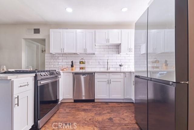 68600 E St, Cathedral City, CA 92234 - kitchen with appliances with stainless steel finishes, a peninsula, a sink, white cabinets, and tasteful backsplash