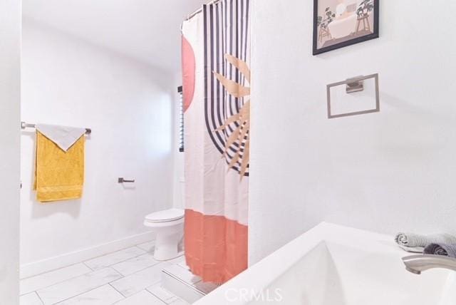 68600 E St, Cathedral City, CA 92234 - bathroom featuring toilet, baseboards, a shower with shower curtain, and marble look tiles