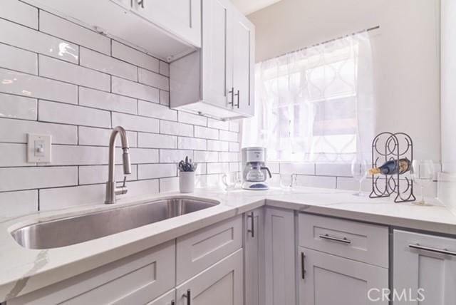 68600 E St, Cathedral City, CA 92234 - kitchen featuring a sink, decorative backsplash, and light stone countertops