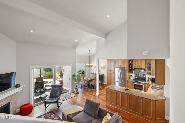 483 Broderick Way, Port Hueneme, CA 93041 - living room featuring high vaulted ceiling, light wood-type flooring, a tiled fireplace, a chandelier, and baseboards