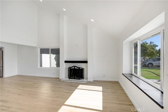 968 N Darfield Ave, Covina, CA 91724 - unfurnished living room with light wood-style flooring, high vaulted ceiling, a fireplace with raised hearth, baseboards, and recessed lighting