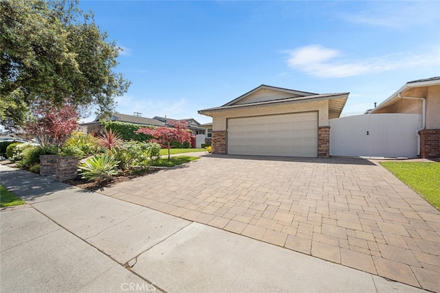 5323 Fidler Ave, Lakewood, CA 90712 - view of front of house with decorative driveway, a gate, an attached garage, stone siding, and stucco siding