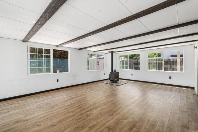 6443 Mount Ackerman Dr, San Diego, CA 92111 - spare room with beam ceiling, a wood stove, wood finished floors, and healthy amount of natural light