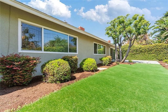 557 S Gardner Dr, Orange, CA 92866 - view of side of property featuring stucco siding, a lawn, and a chimney