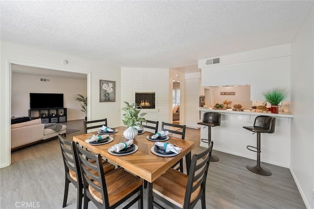 557 S Gardner Dr, Orange, CA 92866 - dining room with a textured ceiling, wood finished floors, baseboards, and a fireplace