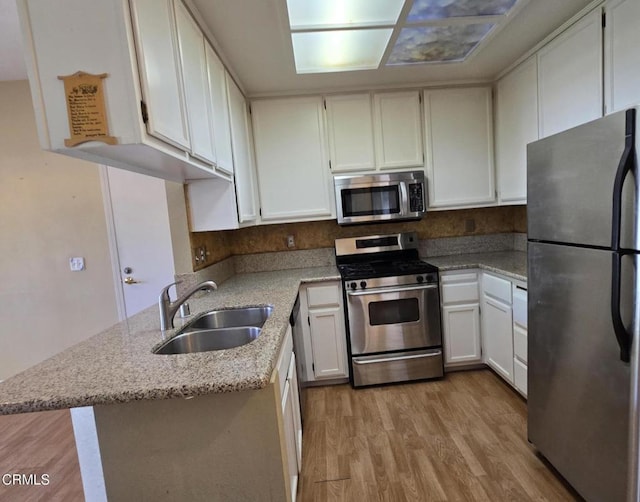 1174 Greene Ter, Davis, CA 95618 - kitchen featuring appliances with stainless steel finishes, a sink, light wood finished floors, light stone countertops, and white cabinets