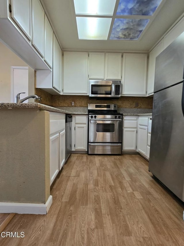 1174 Greene Ter, Davis, CA 95618 - kitchen with appliances with stainless steel finishes, light wood-style flooring, white cabinetry, and tasteful backsplash