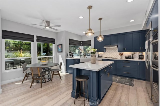 12 Argos, Laguna Niguel, CA 92677 - kitchen featuring blue cabinetry, under cabinet range hood, stainless steel gas stovetop, light countertops, and a center island