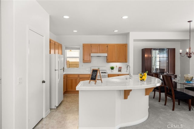 1634 Rigel St, Beaumont, CA 92223 - kitchen with white appliances, tile counters, a sink, under cabinet range hood, and an island with sink