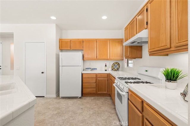 1634 Rigel St, Beaumont, CA 92223 - kitchen with white appliances, under cabinet range hood, tile countertops, and recessed lighting
