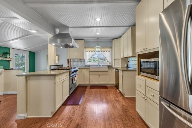 8213 Ocean View Ave, Whittier, CA 90602 - kitchen featuring appliances with stainless steel finishes, wall chimney exhaust hood, a sink, wood finished floors, and backsplash