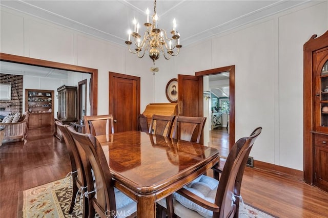 8213 Ocean View Ave, Whittier, CA 90602 - dining room featuring dark wood finished floors, a chandelier, crown molding, a decorative wall, and baseboards