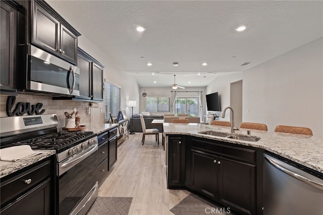 748 Expedition Way W, Madera, CA 93636 - kitchen featuring appliances with stainless steel finishes, a sink, open floor plan, light wood-style floors, and backsplash
