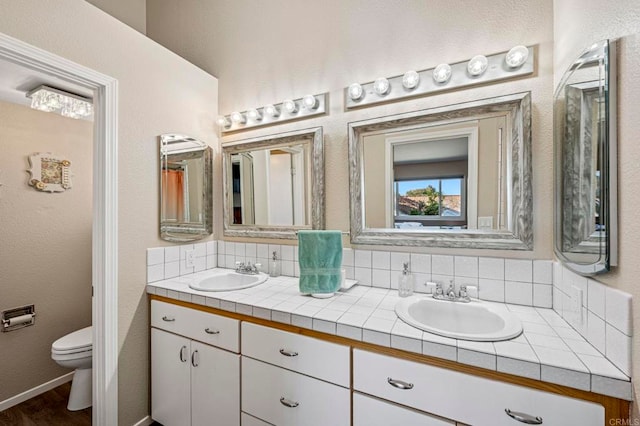 3016 Alta Vista Dr, Fallbrook, CA 92028 - full bathroom featuring double vanity, toilet, backsplash, wood finished floors, and baseboards