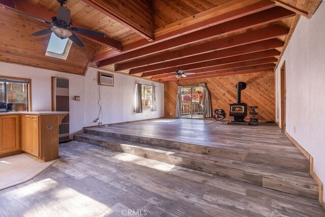 817 E Mountain View Blvd, Big Bear City, CA 92314 - unfurnished living room with a ceiling fan, a wood stove, a heating unit, beam ceiling, and a wall unit AC