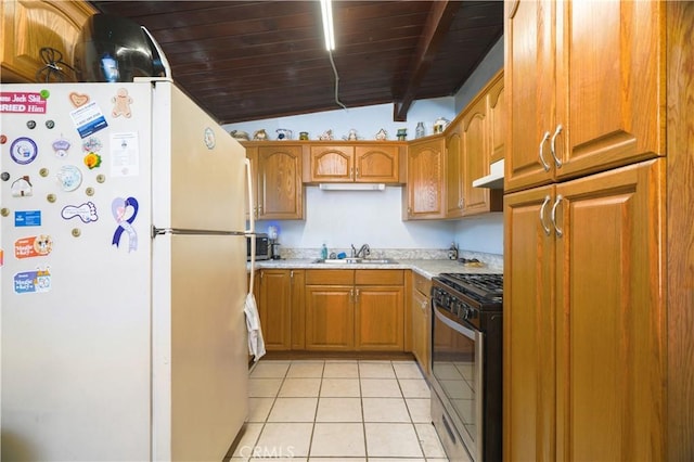 5914 N Rockvale Ave, Azusa, CA 91702 - kitchen featuring freestanding refrigerator, stainless steel range with gas cooktop, under cabinet range hood, light tile patterned floors, and brown cabinetry