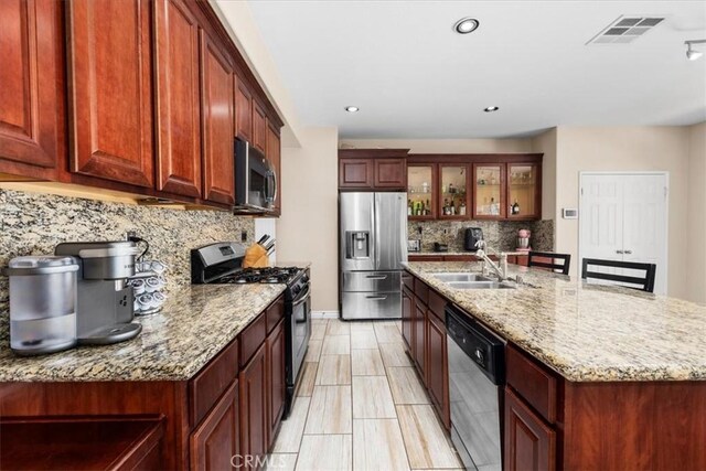 27109 Woodglen Ln, Moreno Valley, CA 92555 - kitchen with stainless steel appliances, a sink, decorative backsplash, a kitchen island with sink, and light stone countertops