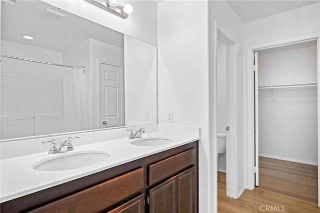 1349 Gordon Ct, Beaumont, CA 92223 - bathroom with double vanity, toilet, wood finished floors, a shower with shower curtain, and a spacious closet