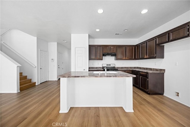1349 Gordon Ct, Beaumont, CA 92223 - kitchen featuring under cabinet range hood, dark brown cabinetry, an island with sink, light wood-style floors, and recessed lighting