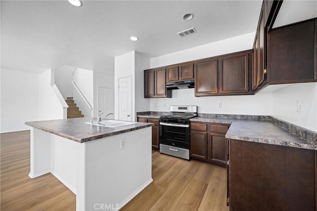 1349 Gordon Ct, Beaumont, CA 92223 - kitchen featuring stainless steel gas range, a sink, under cabinet range hood, dark countertops, and light wood-style floors
