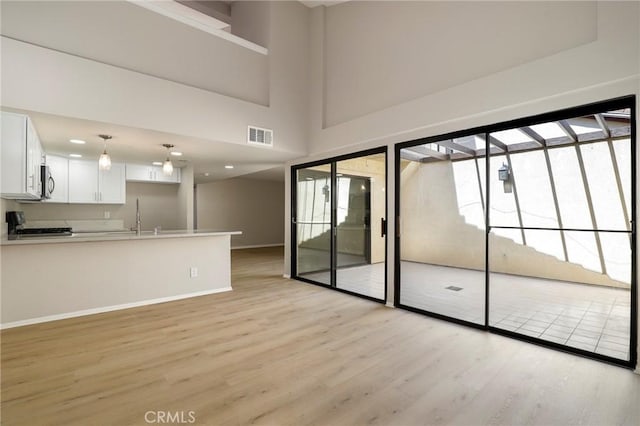 43334 32nd St W Unit 12, Lancaster, CA 93536 - unfurnished living room with light wood finished floors, baseboards, a sink, a towering ceiling, and recessed lighting