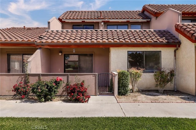 43334 32nd St W Unit 12, Lancaster, CA 93536 - view of front of property with a gate, a fenced front yard, a tile roof, and stucco siding