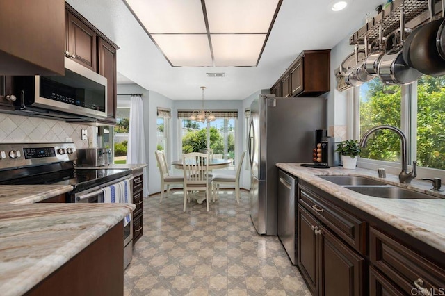 1064 Glen Arbor Dr, Encinitas, CA 92024 - kitchen with appliances with stainless steel finishes, a sink, a chandelier, tasteful backsplash, and dark brown cabinetry