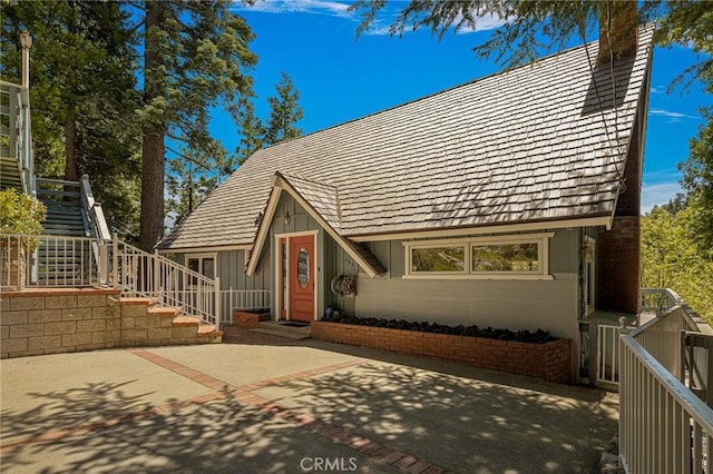 28960 Palisades Dr, Lake Arrowhead, CA 92352 - view of front of house featuring stairway, a chimney, board and batten siding, and a patio area