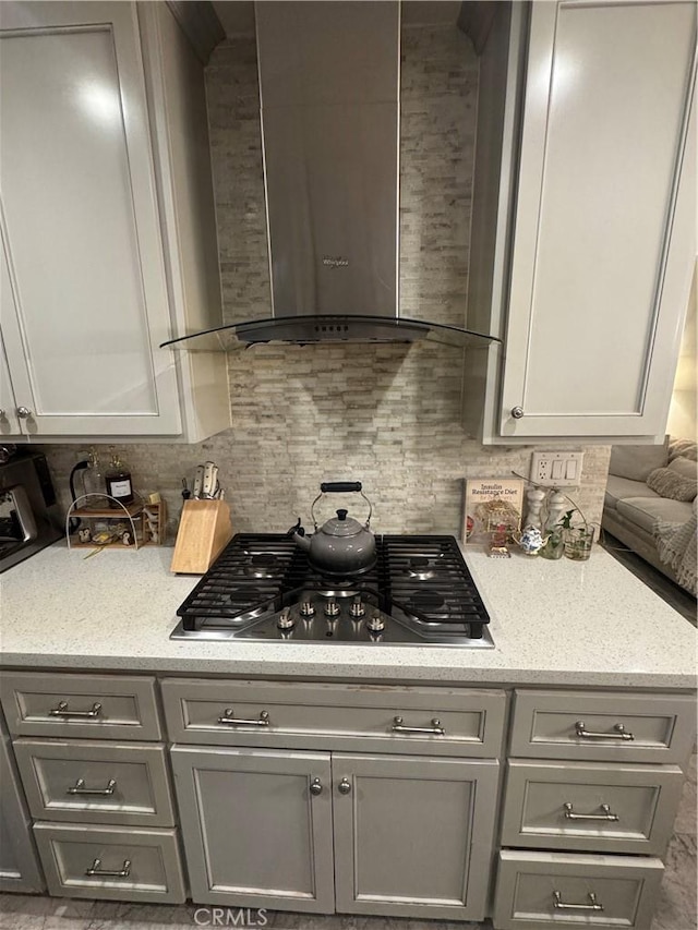 4552 Los Toros Ave, Pico Rivera, CA 90660 - kitchen with wall chimney exhaust hood, gray cabinetry, stainless steel gas stovetop, decorative backsplash, and light stone counters
