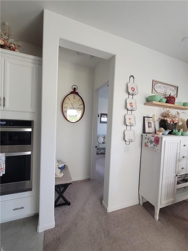 11915 Sagecrest Ct, Corona, CA 92883 - kitchen with stainless steel double oven, white cabinetry, light colored carpet, and baseboards