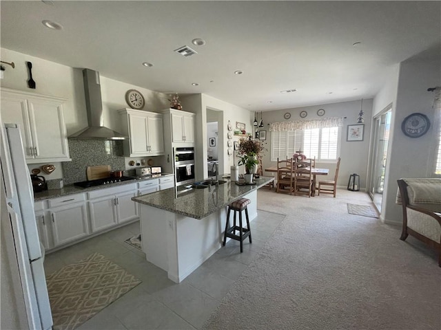 11915 Sagecrest Ct, Corona, CA 92883 - kitchen featuring wall chimney range hood, black electric stovetop, white cabinetry, a breakfast bar area, and recessed lighting