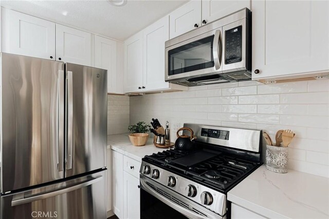26625 Pinehurst Dr, Lake Arrowhead, CA 92352 - kitchen with appliances with stainless steel finishes, white cabinets, decorative backsplash, and light stone countertops