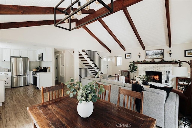 26625 Pinehurst Dr, Lake Arrowhead, CA 92352 - dining area featuring wood finished floors, stairway, beamed ceiling, a fireplace, and high vaulted ceiling