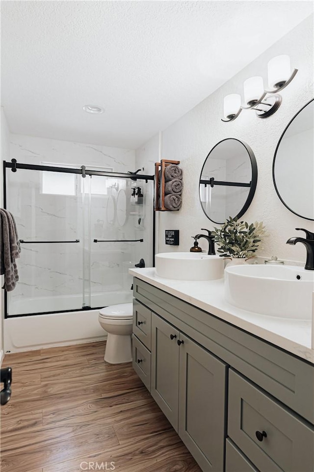 26625 Pinehurst Dr, Lake Arrowhead, CA 92352 - full bath featuring double vanity, combined bath / shower with glass door, toilet, a textured ceiling, and wood finished floors