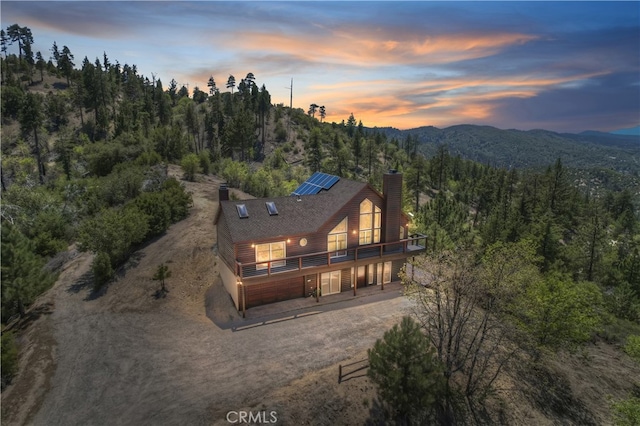 175 N Trails End Rd, Green Valley Lake, CA 92341 - back of house featuring a chimney, driveway, solar panels, a forest view, and a deck with mountain view