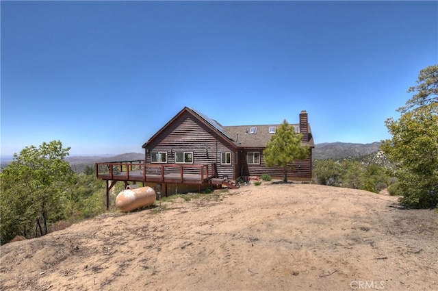 175 N Trails End Rd, Green Valley Lake, CA 92341 - back of property with a deck with mountain view, a chimney, and log veneer siding