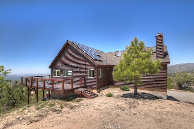 175 N Trails End Rd, Green Valley Lake, CA 92341 - view of side of property with roof mounted solar panels, a wooden deck, a shingled roof, and a chimney