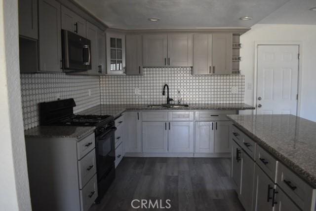 815 California Ave, Dos Palos, CA 93620 - kitchen featuring black range with gas cooktop, a sink, stone countertops, open shelves, and dark wood-type flooring